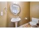 Half bathroom featuring pedestal sink, round decorative mirror, and neutral color palette at 1301 Durlain Dr # 103, Raleigh, NC 27614