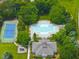 Aerial view of community amenities including a pool, tennis court, playground, and clubhouse, surrounded by trees at 1308 Woodgate Manor Ct, Raleigh, NC 27614