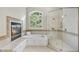 Elegant bathroom featuring a soaking tub, glass-enclosed shower, and a cozy fireplace at 1308 Woodgate Manor Ct, Raleigh, NC 27614