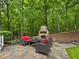 Inviting outdoor living area featuring a stone fireplace, seating, and a flagstone patio surrounded by lush greenery at 1308 Woodgate Manor Ct, Raleigh, NC 27614