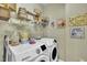 Bright laundry room with washer, dryer, shelving, and unique vintage laundry decor at 133 Marino Pl, Clayton, NC 27527