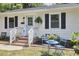 Close up of a charming single-story home with light blue door and cozy front yard seating area at 1408 Ida St, Durham, NC 27705