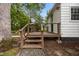 Back porch with wooden steps and railing leading to a backyard with a fire pit and patio at 1541 Shadylawn Dr, Burlington, NC 27215
