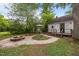 Backyard featuring a fire pit, garden area, patio table with umbrella, and mature trees at 1541 Shadylawn Dr, Burlington, NC 27215