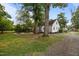 Charming home featuring an outdoor fire pit, mature trees, and a gravel driveway at 1541 Shadylawn Dr, Burlington, NC 27215