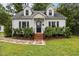 Charming Cape Cod home with dormer windows, black shutters, brick steps, and mature landscaping at 1541 Shadylawn Dr, Burlington, NC 27215
