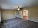 Spacious living room with neutral carpet, ceiling fan, and archway leading to the bright, white kitchen at 195 Washington Ln, Cameron, NC 28326