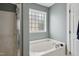 Bathroom featuring a tiled shower and garden tub beneath a frosted glass window at 2004 Tennessee Rd, Durham, NC 27704