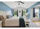 Bright bedroom features blue accent wall, ceiling fan, and large windows offering backyard views at 2004 Tennessee Rd, Durham, NC 27704