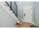 Modern entryway featuring light blue walls, wooden floors, a staircase with black railings, and a white door at 2004 Tennessee Rd, Durham, NC 27704