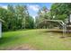 Large carport providing ample covered parking or storage space in a serene, green backyard at 202 Hamilton Rd, Bunnlevel, NC 28323