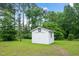 A well-maintained, white outbuilding sits in a sunny, verdant yard, perfect for storage at 202 Hamilton Rd, Bunnlevel, NC 28323