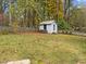 Spacious backyard with mature trees, a wooden fence, and a charming storage shed at 203 W Boundary St, Cary, NC 27513