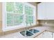 Close-up of the kitchen sink with a view of the landscaped yard through the window and granite countertops at 205 Slate Blue Pl, Cary, NC 27519