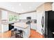 Bright kitchen features white cabinets, stainless appliances, granite counters, hardwood floors, and island with bar seating at 205 Slate Blue Pl, Cary, NC 27519