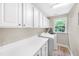 Bright laundry room featuring built-in cabinets, counter space, window, and modern washer and dryer at 205 Slate Blue Pl, Cary, NC 27519