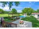 Lush backyard featuring a pergola with seating, a fire pit, an in-ground pool, and a pool house at 2925 Redwood Rd, Durham, NC 27704