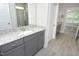 A bathroom featuring a granite vanity, gray cabinets, and a doorway leading to a bedroom with carpet at 309 Hines Point Dr, Rolesville, NC 27571