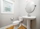 Charming powder room with pedestal sink, round mirror, and natural light at 3129 Elm Tree Ln, Raleigh, NC 27614