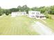 An aerial view of a two-story home with a long driveway, surrounded by green lawn and lush trees at 3354 Altamahaw Church Rd, Elon, NC 27244