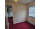 A bedroom with red carpeting, cream walls, and a small window for natural light at 3354 Altamahaw Church Rd, Elon, NC 27244