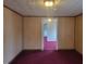 A carpeted living room with wood paneling and views into another room at 3354 Altamahaw Church Rd, Elon, NC 27244