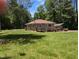 A delightful property with a green lawn, a cozy home, and a covered carport amidst a wooded backdrop at 3405 Ode Turner Rd, Hillsborough, NC 27278