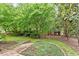 Lush backyard with manicured landscaping, mature trees, storage shed, and hardscape at 3509 Carlton Square Pl, Raleigh, NC 27612