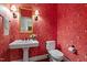 Charming powder room with pedestal sink, decorative mirror, sconces, and bright floral wallpaper at 3509 Carlton Square Pl, Raleigh, NC 27612