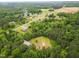 Scenic aerial view of a property with a mix of wooded areas, cleared land, and a house with ample parking at 3906 Union Ridge Rd, Burlington, NC 27217
