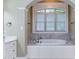 Elegant bathroom with a large soaking tub, arched window, and stylish fixtures that create a spa-like retreat at 504 Belmont Cir, Wake Forest, NC 27587
