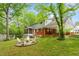 Backyard view of the home featuring a screened-in porch, patio, fire pit, and mature trees at 504 S Dixon Ave, Cary, NC 27511