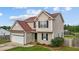 Charming two-story home featuring tan siding, brown roof, attached two car garage, and manicured landscaping at 5321 Longspur Dr, Snow Camp, NC 27349