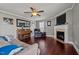 Cozy living room featuring hardwood flooring, fireplace, piano, and ceiling fan with great natural light at 5321 Longspur Dr, Snow Camp, NC 27349