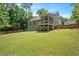 View of the home's backyard, featuring a green lawn, a screened porch, and a wooden fence at 6512 Blalock Forest Dr, Willow Springs, NC 27592