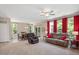 Bright living room featuring a ceiling fan, large windows with red drapes, and an open floor plan at 6512 Blalock Forest Dr, Willow Springs, NC 27592