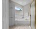 Bright bathroom featuring a soaking tub with tile surround, storage cabinets, and natural light from a window at 6728 Pointe Vista Cir, Raleigh, NC 27615