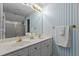 Bathroom featuring dual sinks with marble counters, blue striped wallpaper, and a shower with gold trim at 6728 Pointe Vista Cir, Raleigh, NC 27615