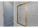 Close-up of a shower with a gold frame and sliding glass door, complemented by blue striped wallpaper at 6728 Pointe Vista Cir, Raleigh, NC 27615