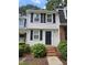 Charming two-story townhome with black shutters, brick stairs, and lush green landscaping at 7719 Kingsberry Ct, Raleigh, NC 27615