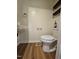 Cozy powder room featuring hardwood floors, pedestal sink, and floating wood shelves at 7719 Kingsberry Ct, Raleigh, NC 27615