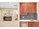 Stylish wet bar with rich wood cabinets, mosaic backsplash, granite countertop, and elegant fixtures at 8 Pine Top Pl, Durham, NC 27705