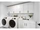 Modern laundry room with white cabinets, countertop space, sink, and front load washer and dryer at 1020 Dillon Lake Dr, Knightdale, NC 27545