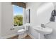Powder room with a round mirror, pedestal sink, and a window showing a view of lush green trees at 103 Ailey Brook Way # 200, Wake Forest, NC 27587