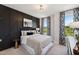 A stylish bedroom with a black paneled accent wall, a metal frame bed, and bright natural light at 103 Ailey Brook Way # 200, Wake Forest, NC 27587
