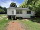 Back exterior showcasing the home's vinyl siding and windows, plus backyard and two large garbage bins at 1202 Kilby St, Burlington, NC 27215