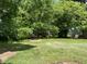 Expansive backyard view featuring mature trees, green grass, and an outbuilding at the rear of the property at 1202 Kilby St, Burlington, NC 27215