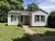 Traditional single-story home with classic siding and shutters, surrounded by mature trees and a green lawn at 1202 Kilby St, Burlington, NC 27215