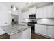 Bright kitchen featuring granite countertops, stainless steel appliances, white cabinetry, and tile backsplash at 170 Kinsale Ct, Garner, NC 27529