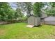 Backyard featuring green grass, mature trees, shed, and privacy fence at 1801 Sagamore Ct, Raleigh, NC 27604